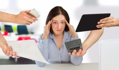 A young woman rubs her temples while other are showing her the screens of differenct devices. 