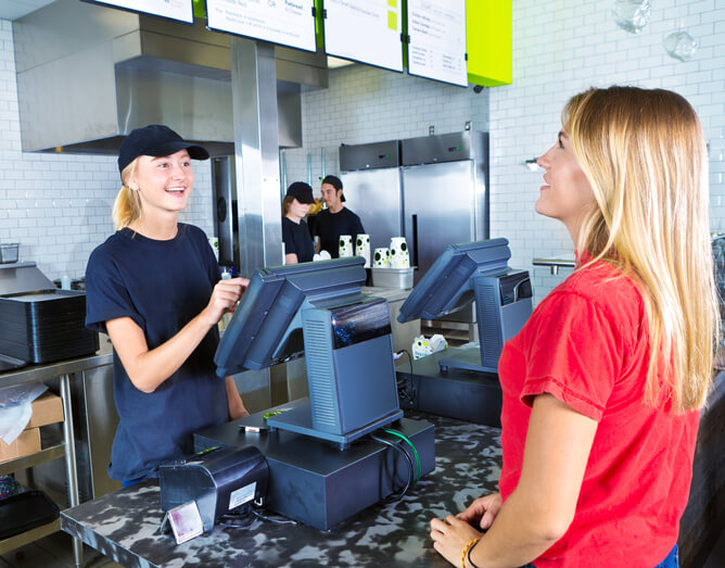 A cashier taking a customer's order on the kiosk.