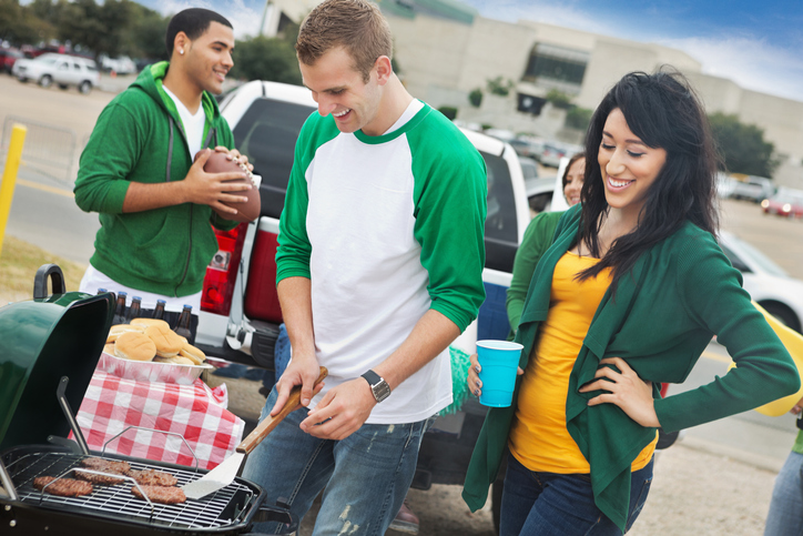 Group of friends enjoying grilled food in the stadium parking lot.