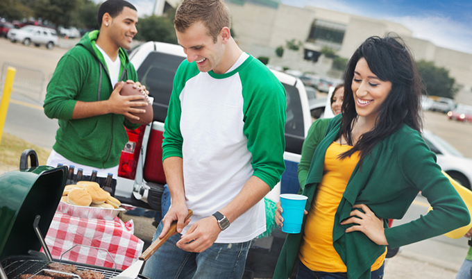 Group of friends enjoying grilled food in the stadium parking lot.