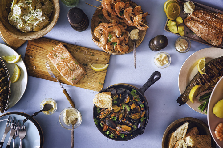 View of seafood themed dishes including shrimp, salmon, clams.