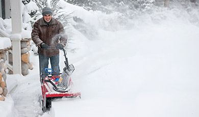 Man snow blowing his walk. 