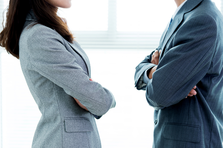 Two co-workers with their arms crossed and facing each other.