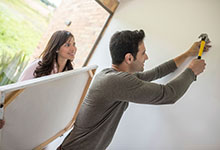 Two people hanging a painting. 